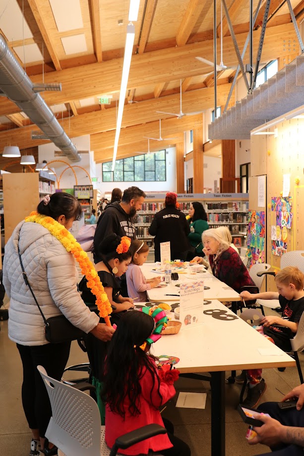 Photo of community engaging with library crafting tables during Dia de los muertos 2024.